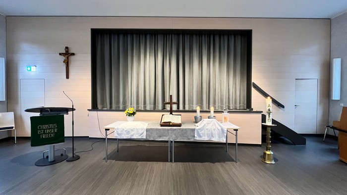 Ein moderner Kirchenraum mit Altar, Kreuz und Podium