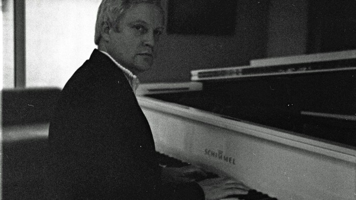 Ein Mann spielt Klavier in einem Raum.
