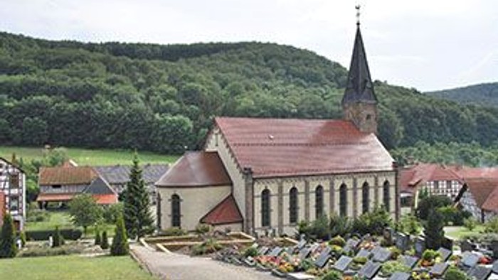 Kirchhof mit Kirche und Grabsteinen im Dorf
