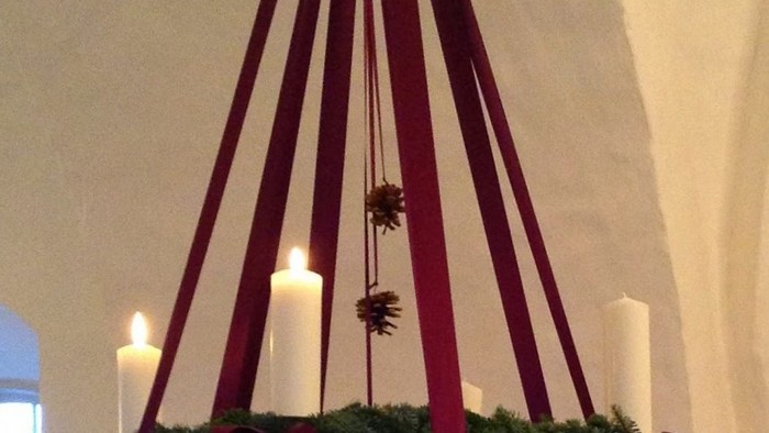 En hængende juledekorasjon med grønne blomster og lysende lygter.