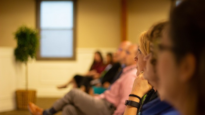 Einige Menschen sitzen in einem Raum, einer mit einem Baby.