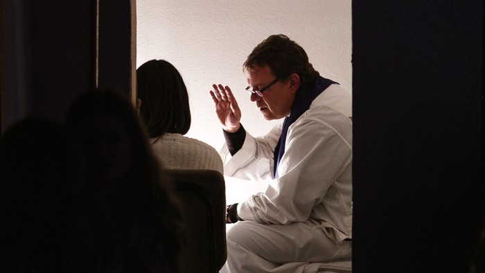 Ein Mann in weißem Anzug winkt auf einer Bühne.