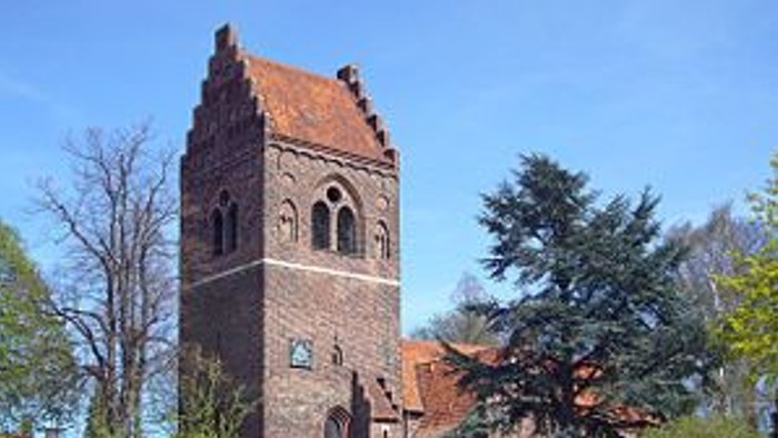 En gammel kirke med tårn og murer i en by.