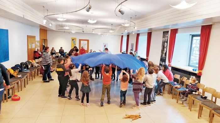 Kinder und Erwachsene spielen in einem Raum mit Regenschirmen.