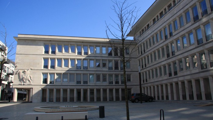 Großer Platz vor modernem Bürogebäude mit vielen Fenstern und Säulen