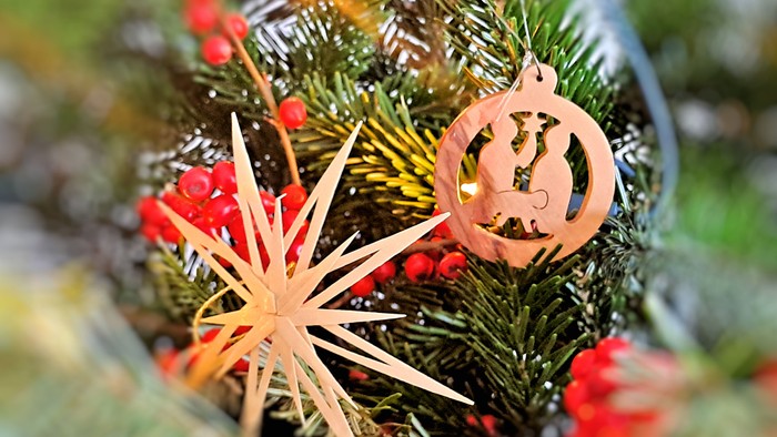 Ein Weihnachtsbaum mit Holzschmuck und roten Beeren