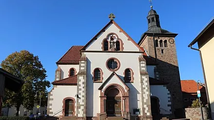 Kirche mit hohem Glockenturm und rotem Dach vor blauem Himmel