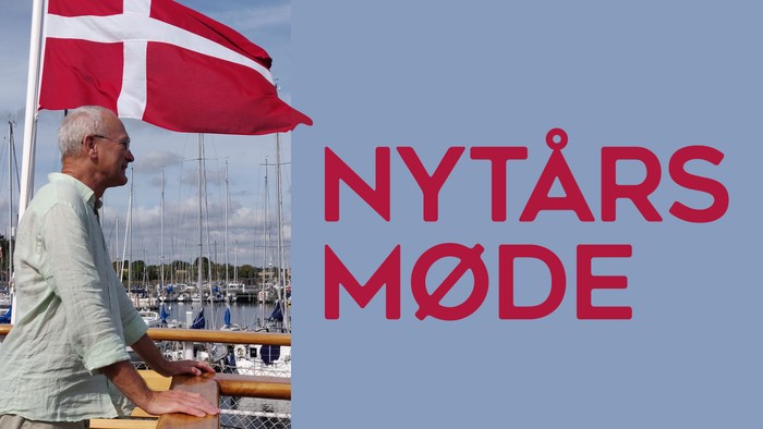 En mand ved en havn vinker med et dansk flag, mens han fejrer nytår med teksten 