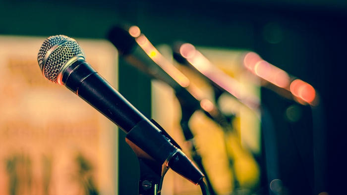 Ein Mikrofon auf einem Ständer vor einem unscharfen Bühnenhintergrund
