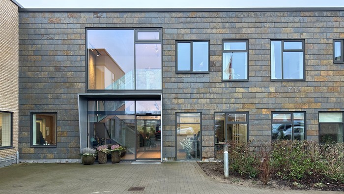 Moderne bygning med store vinduer og indplanteret græs.