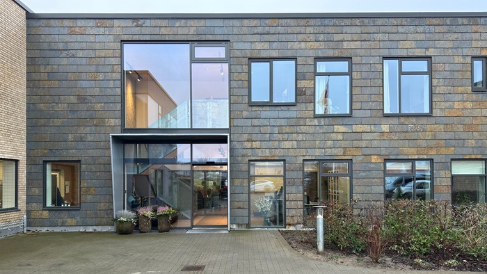 Moderne bygning med store vinduer og indplanteret græs.