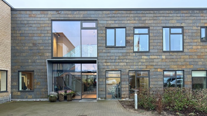 Moderne bygning med store vinduer og indplanteret græs.