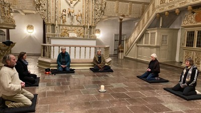 Eine Gruppe von Menschen meditiert in einer geschmückten Kirche.