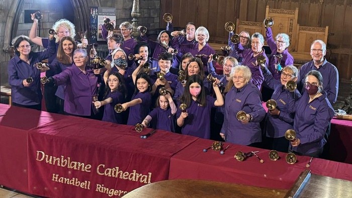 Group of people holding musical instruments posing for a photo.
