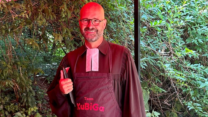 Mann mit Schürze und Hut, der ein Daumen-hoch-Zeichen gibt.