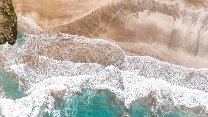 Mächtige Welle bricht an felsiger Küste