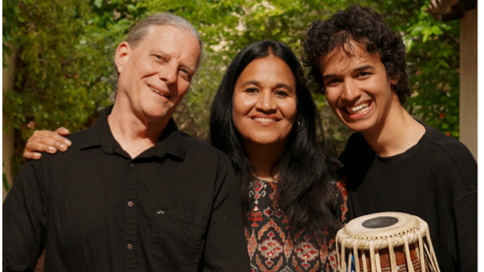 Trois personnes sourient, deux jouent des instruments de musique