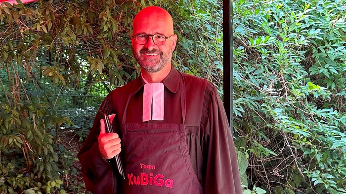 Mann mit Schürze und Hut, der ein Daumen-hoch-Zeichen gibt.