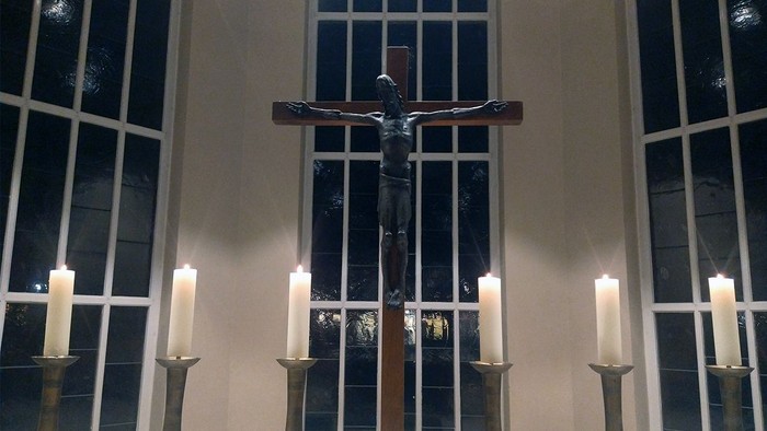 Im Kircheninneren dominiert ein großes Kruzifix, flankiert von Kerzenleuchtern