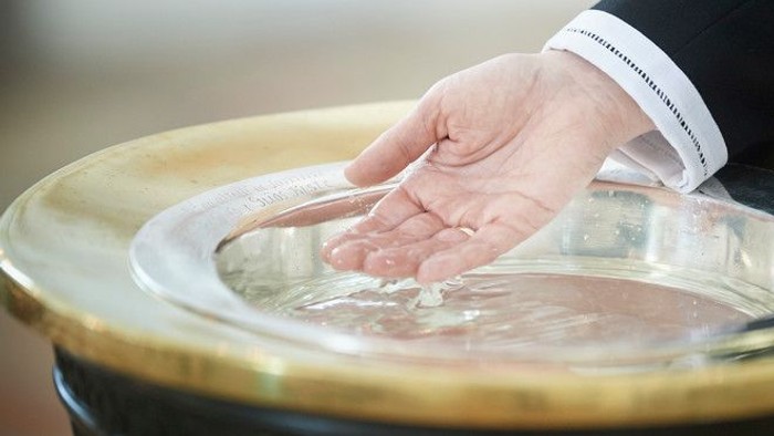 En hånd riner vand i en søppe.