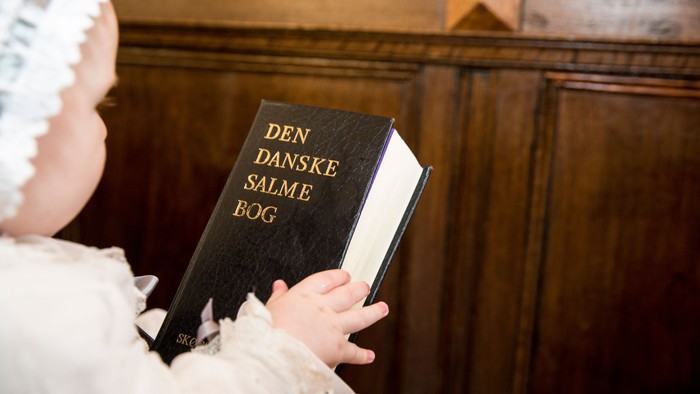 Børn med hvidt hårbånd holder en bog med titlen 