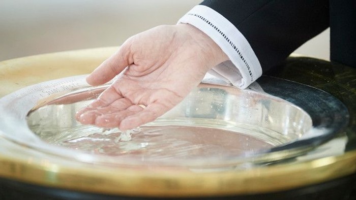 En hånd riner vand i en søppe.