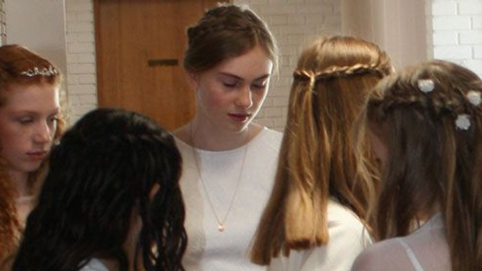 En gruppe piger med smykker og hårbånd står sammen i et rum.