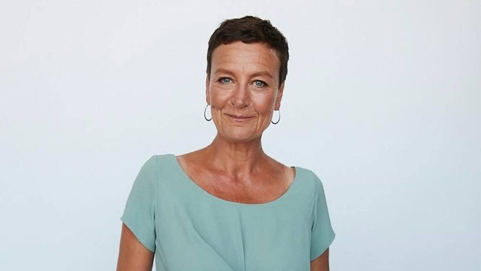 En kvinde i blå outfit med knæbånd og kort hår.