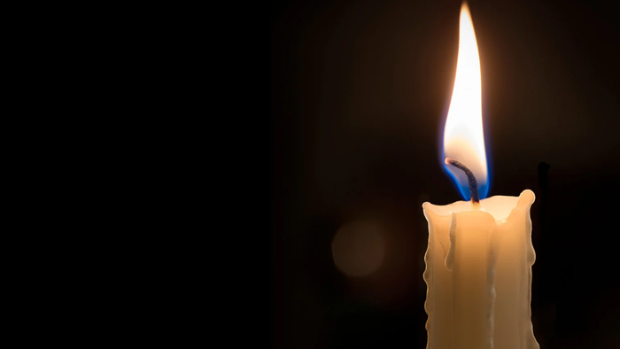 Et enkelt stearinlys flimrer klart mod en mørk baggrund med en blød blå flamme.