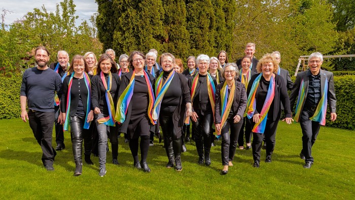 Eine Gruppe von Menschen posiert im Garten, alle mit Regenbogenfahnen geschmückt