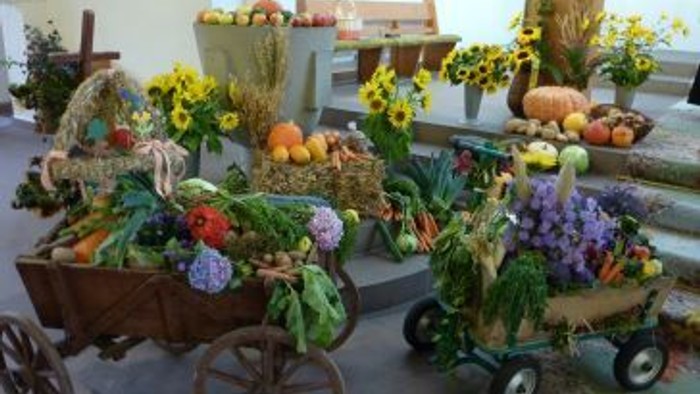 Bunte Wagenausstellungen voller Herbstgemüse, Blumen und Erntedekorationen.