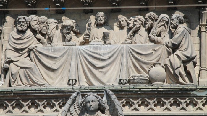 Die Statue zeigt eine Gruppe von Menschen um einen Tisch versammelt.