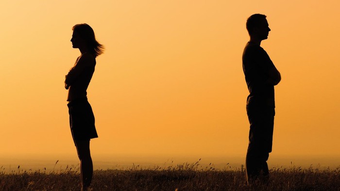 To par står med ryggen til hinanden ved solnedgang.
