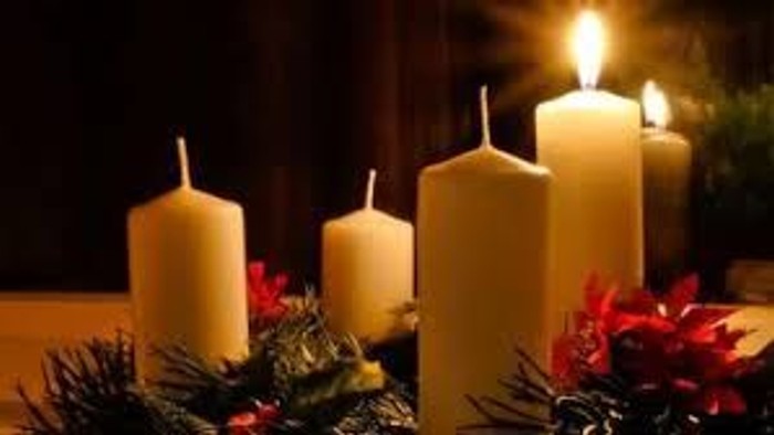 En juledekorasjon med tre lysende lysekøn og grønne blomster.