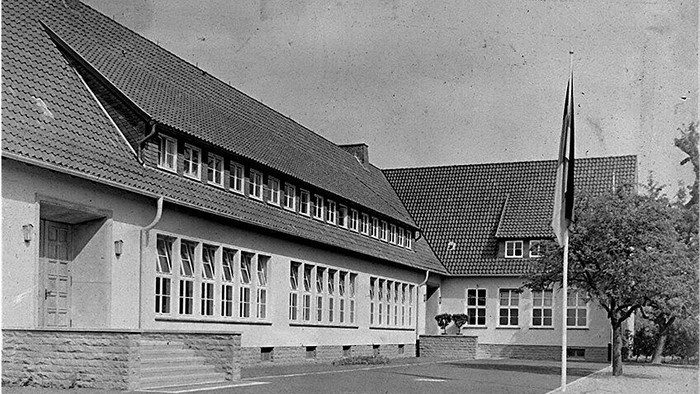 Schwarz-Weiß-Foto eines großen Gebäudes mit vielen Fenstern und einem Flaggenmast.
