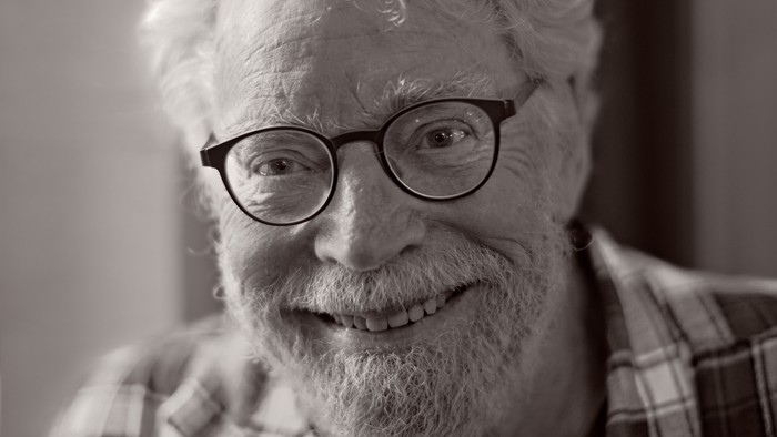 En glad, ældre mand med hvidt hår og briller.