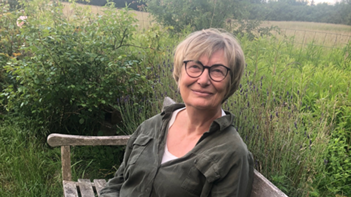 kvinde med briller i grønt tøj på bænk i naturen