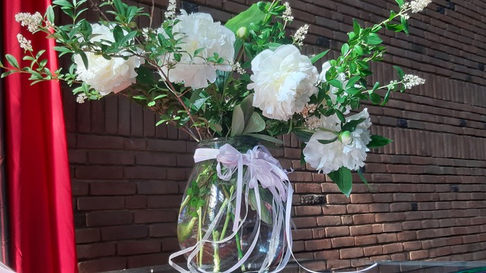 Weiße Blumen in einer Vase auf einer roten Tischdecke.