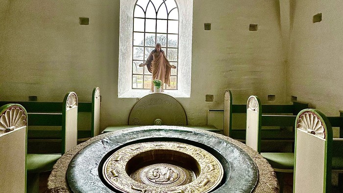 En kirke med en stor stenfont og hvidt bænke.