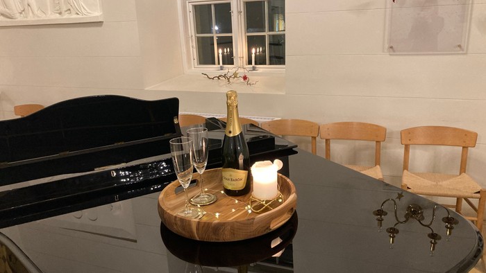 Køkkenbord med vinglas, flaske og stearinlys ved siden af træstole