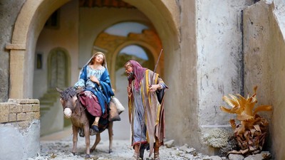 En lille figurinscenografi af Maria og Josef på kamelen under en buet gang.
