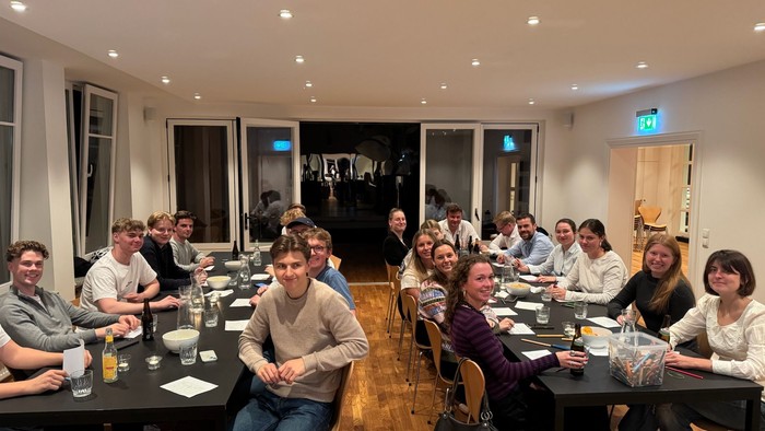 Gruppe af mennesker samlet til en formel middag eller møde med drinks og samtale i et hyggeligt lokale.
