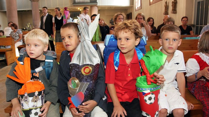 Vier Jungen sitzen in einer Kirche und halten Geschenke