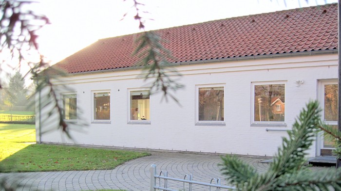 Hus med rødt tag og hvide vinduer.