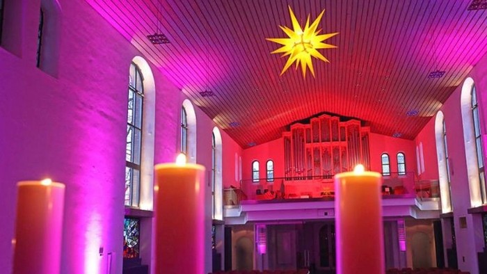 In der Kirche brennen Kerzen, die Orgel ist beleuchtet