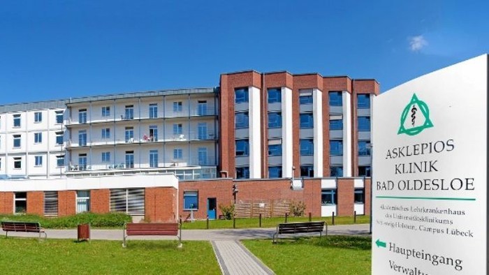 Das Bild zeigt ein modernes Krankenhausgebäude mit viel Grünfläche und Parkplätzen.