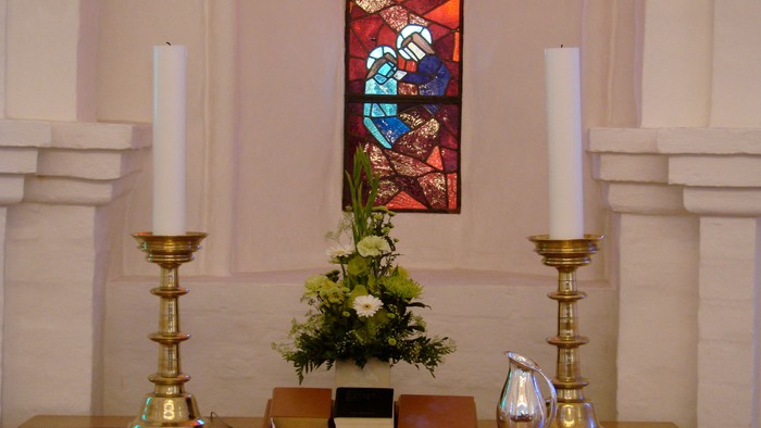 Alter med lysstake, blomsterarrangement og bøger