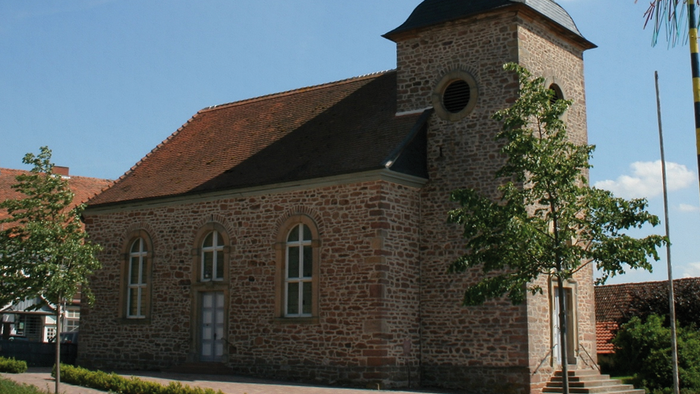 Kirchengebäude mit hohem Turm und spitzem Dach unter blauem Himmel