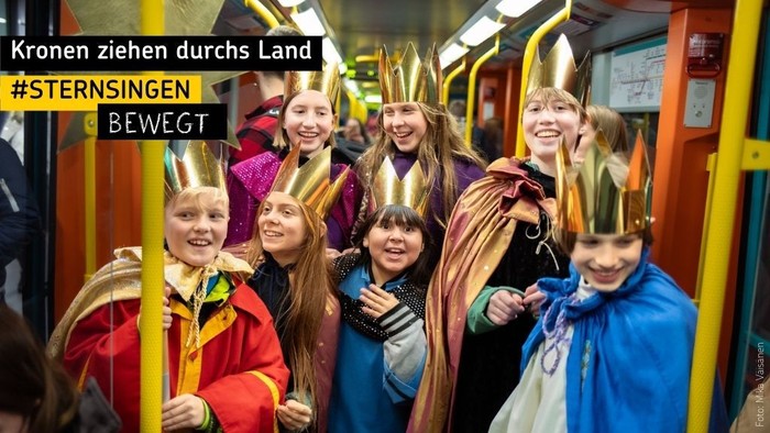 Kinder in Kostümen und Kronen posieren gemeinsam in einem Bus.