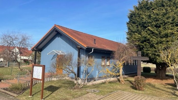 Ein blaues Haus mit rotem Dach und einem kleinen Garten.
